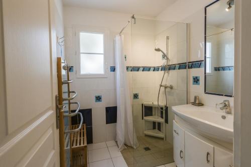a white bathroom with a shower and a sink at Villa Sarment Oleron in Saint-Pierre-dʼOléron