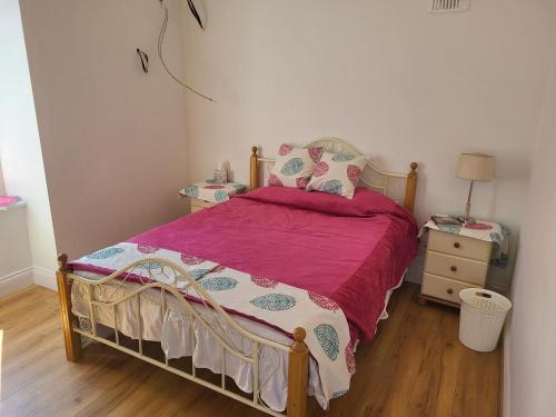 a bedroom with a bed with a pink bedspread at Farm Cottage in Athy