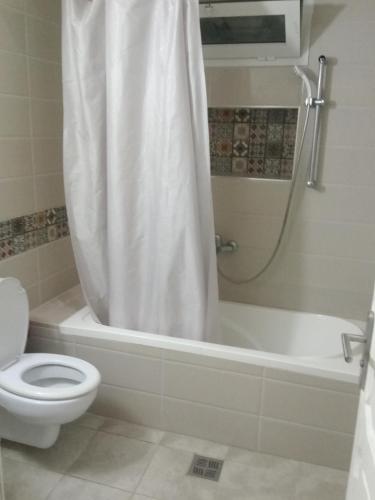 a bathroom with a toilet and a shower with a shower curtain at Darna in Raʼs al Jabal