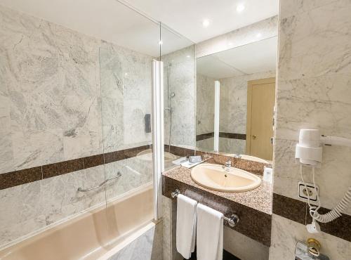ein Badezimmer mit Waschbecken, Badewanne und Spiegel in der Unterkunft Zenit Diplomatic in Andorra la Vella
