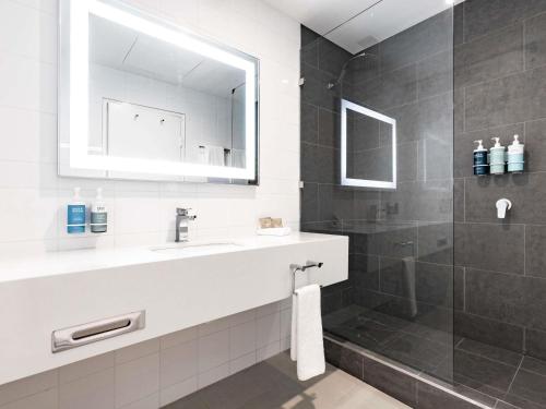 a bathroom with a sink and a shower at Novotel Melbourne Glen Waverley in Glen Waverley