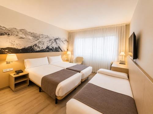 ein Hotelzimmer mit zwei Betten und einem Fernseher in der Unterkunft Zenit Diplomatic in Andorra la Vella