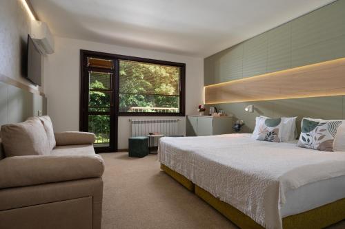 a bedroom with a bed and a chair and a window at Bile - Family Hotel & Gastro Bar in Beli Osŭm