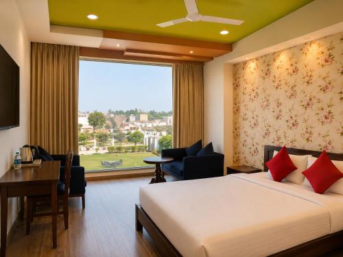 a hotel room with a bed and a desk and a window at Hotel Vrindavan Sultanpur in Sultānpur