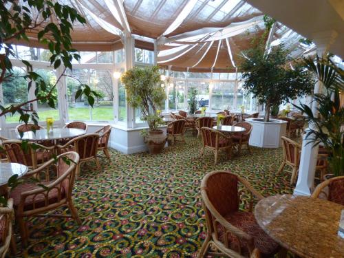 a restaurant with tables and chairs and plants at Arundel House Hotel in Cambridge