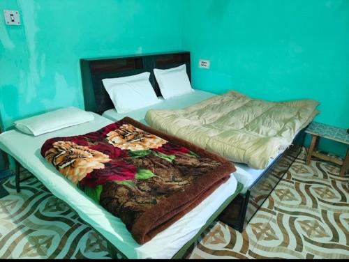 two twin beds in a bedroom with a blue wall at Hariyali Homestay in Sari