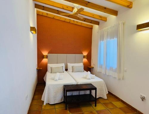 a bedroom with a bed with white sheets and a window at Secrets Rural House in Jávea
