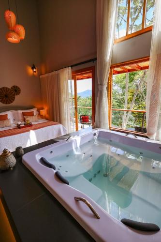 a large bath tub in a room with two beds at Fruto Vermelho Pousada in Pedra Menina