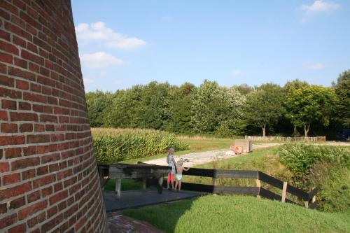 a woman standing on a wooden bridge next to a brick wall at Het Torentje van Trips in Tripscompagnie