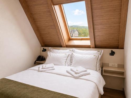 a bedroom with a white bed with a window at Hotel O2 Tornik in Ribnica