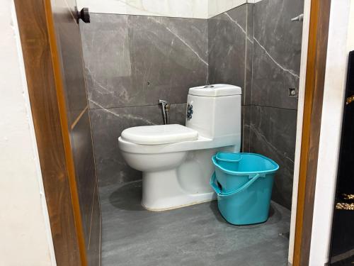 a bathroom with a toilet and a blue trash can at Roys Rooms in Kumarakom