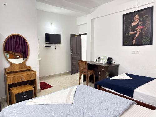 a hotel room with two beds and a desk and a table at Roys Rooms in Kumarakom