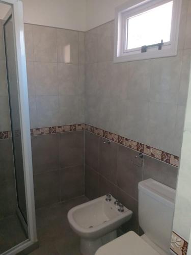 a bathroom with a toilet and a sink and a window at Lo de Rolo in Huerta Grande