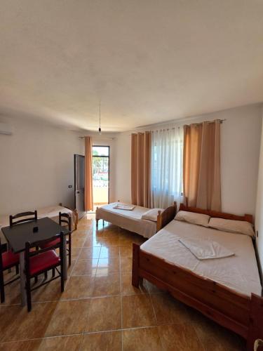 a room with two beds and a table and a desk at Vila Flamuri in Golem