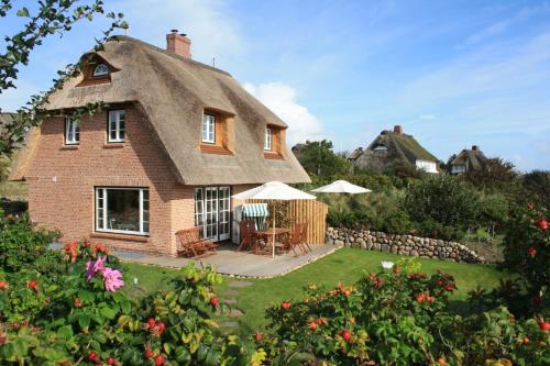 a house with a thatched roof with a patio at Haus Düne in List