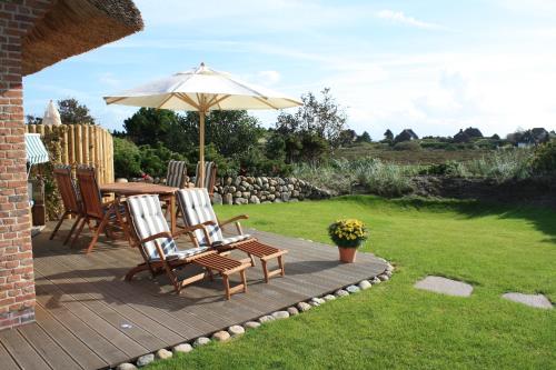 a patio with a table and chairs and an umbrella at Haus Düne in List