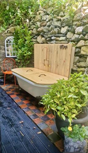 a bath tub sitting next to a stone wall at Waterfall retreat in Blaenau-Ffestiniog