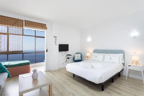 a bedroom with a bed and a couch and a tv at Don Rafael # Ocean views # Natural pools in Bajamar