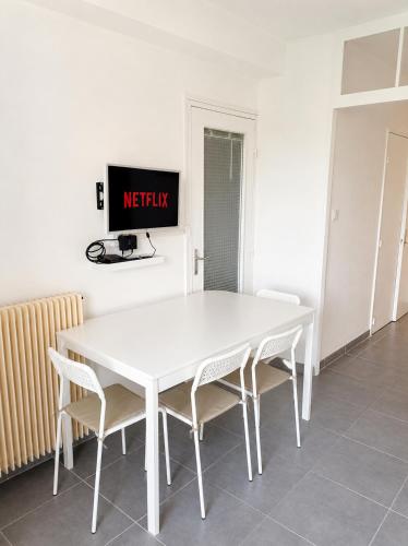 a white table and chairs in a room with a tv at L'Albatros - Appartement de charme à Digoin in Digoin