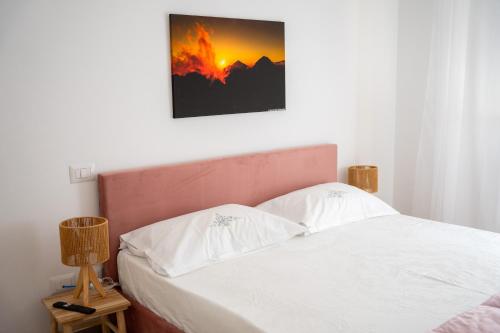 a bedroom with a white bed with a picture on the wall at 99 Rooms in LʼAquila