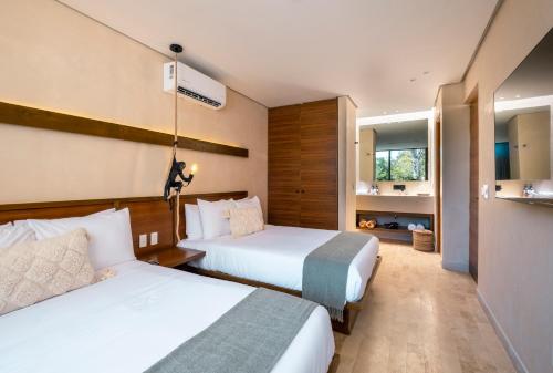 ein Hotelzimmer mit zwei Betten und einem Badezimmer in der Unterkunft Collection O Faisano Boutique Luxury Hotel, Tulum Beach in Tulum