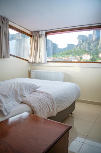 a bedroom with a bed and a large window at Hotel Kosta Famissi in Kalabaka