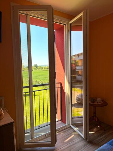 an open sliding glass door with a view of a field at Sala dell Estate Guest House in Secchia