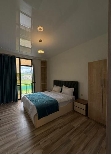 a bedroom with a bed and a large window at Pinevillasadgeri in Borjomi