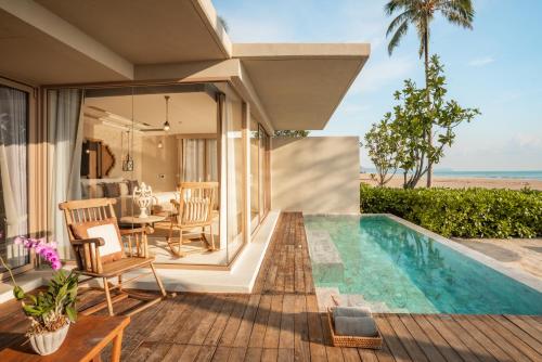 a villa with a swimming pool and a patio at Devasom Khao Lak Beach Resort & Villas in Khao Lak