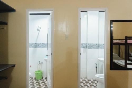 a bathroom with a shower and a toilet and a mirror at Jared Suites in Upper Digos
