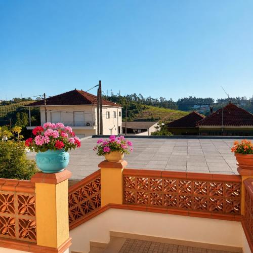 a balcony with flowers in pots on a fence at Casa da Risca Amarela in Leiria