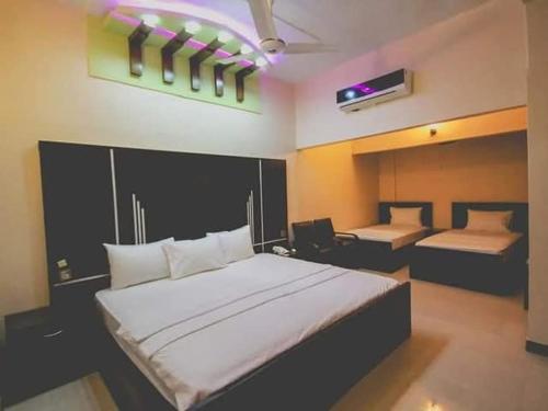 a bedroom with a large white bed and a desk at The R Hotels Nursery in Karachi
