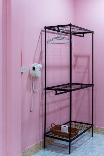 a pink room with a black shelf and a pink wall at PoonsukPlace Sampran in Ban Bang Yai Chuai