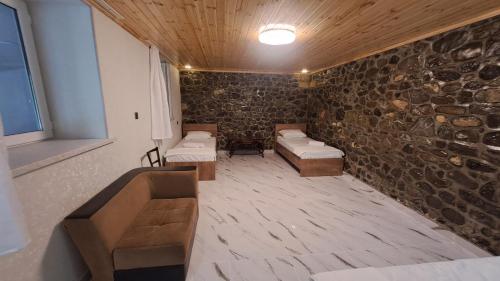 a room with couches and a stone wall at Old Rooms in Sheki
