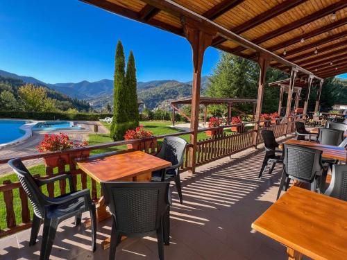 a patio with tables and chairs and a view of the mountains at Хотел Кючуковата Къща in Banite
