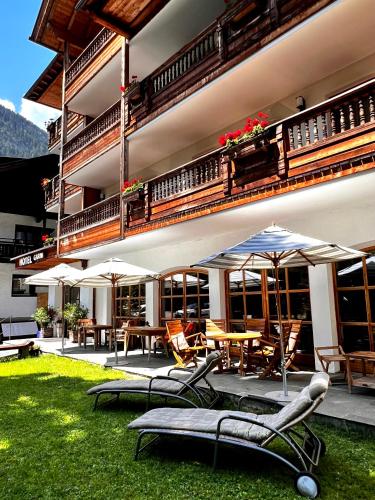an outdoor patio with chairs and tables and umbrellas at Hotel Garni Obermair in Mayrhofen