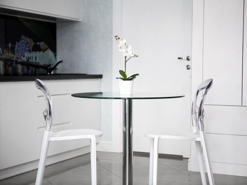 a glass table with two chairs and a vase with flowers at Softly Residence in Bydgoszcz