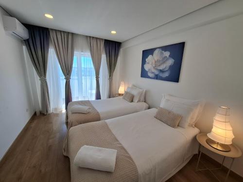 a hotel room with two beds and a window at Thouse Fontainhas in Cascais