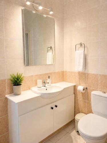 a bathroom with a sink and a toilet and a mirror at Athena Apartment in Polis Chrysochous