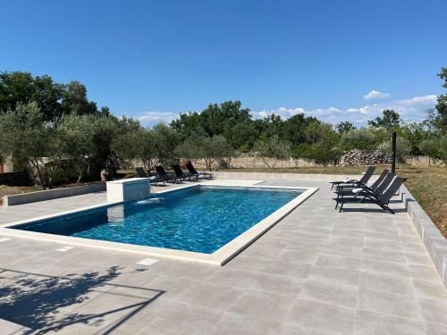 a swimming pool in a patio with chairs around it at Pax et Bonum in Lozovac