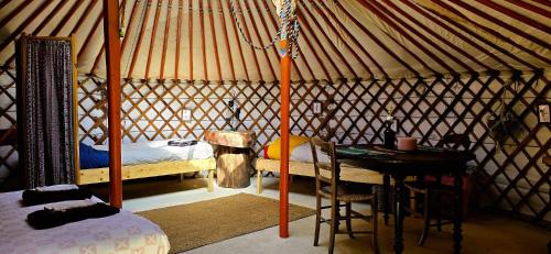a room with a bed and a table in a yurt at Le portillon des fées in Sost