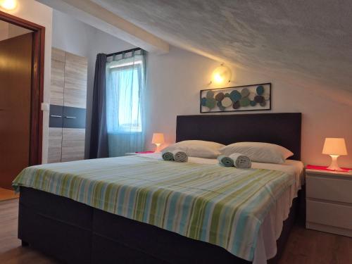 a bedroom with a large bed with a striped blanket at Apartments Tea Pag in Pag