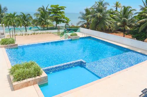 a large blue swimming pool with palm trees and the ocean at Magico Apartamento Frente al Mar 3 Habitaciones TR72 in Guayabal