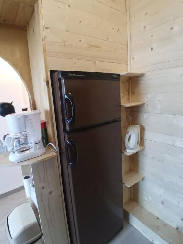 a black refrigerator in a tiny kitchen with wooden walls at Profitez de la vue in Ustou