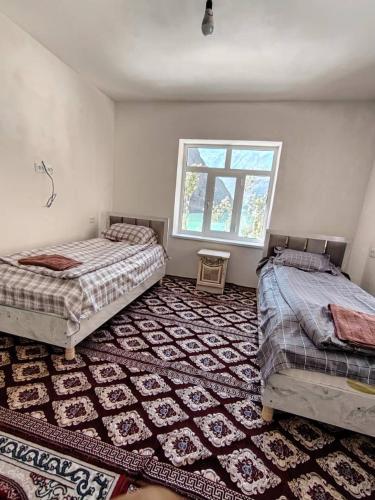 a bedroom with two beds and a large rug at Nofin Lake House in Panjakent