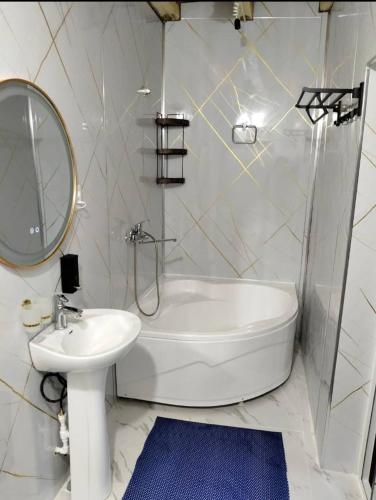 a bathroom with a tub and a sink and a mirror at Nofin Lake House in Panjakent