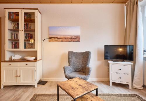 a living room with a chair and a television at Haus Schildt, FeWo 7 in Duhnen