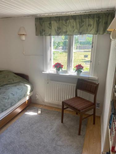 a bedroom with a bed and a chair and two windows at Röda huset in Åhus