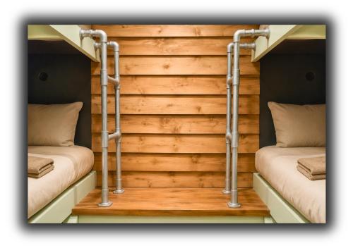 two beds in a room with wooden walls at Pitchside Rooms in Liverpool