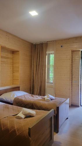 two beds in a room with wooden walls at Guest House Adelina in Mestia